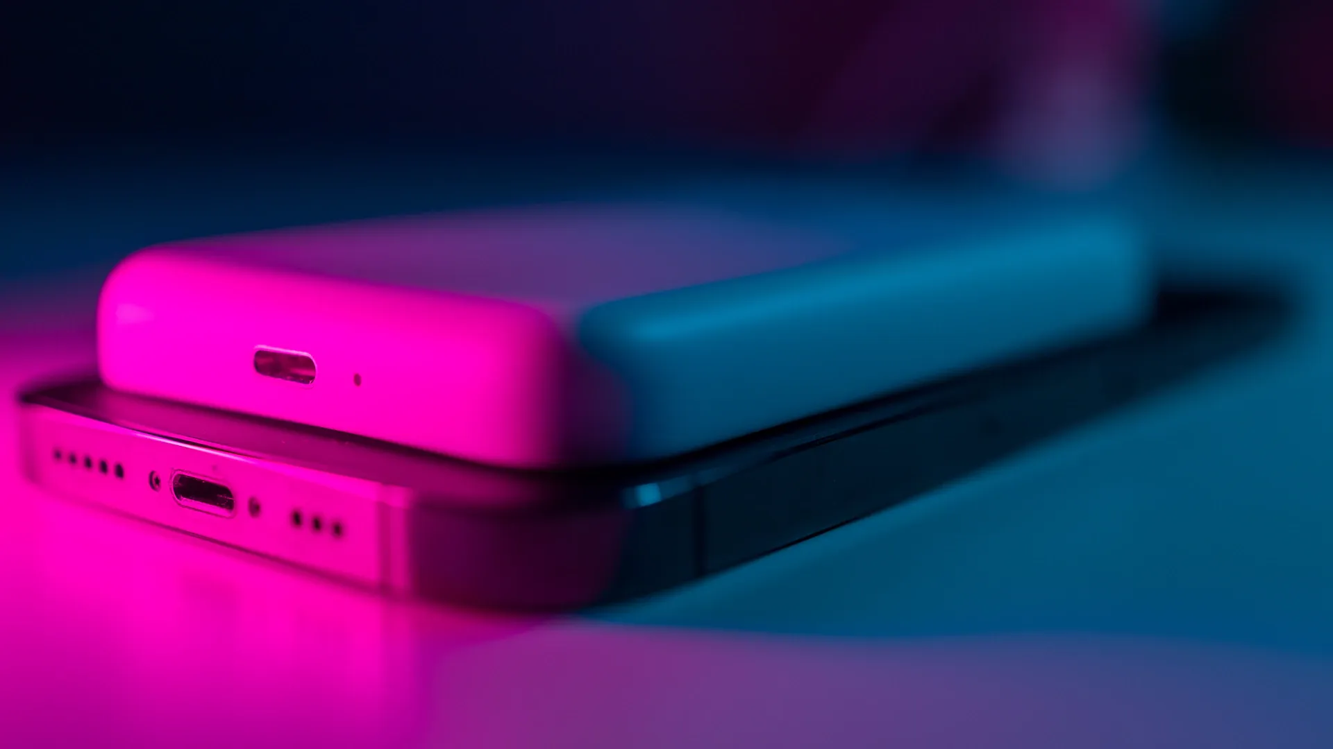 Batterie externe MagSafe posée sur un smartphone sous un éclairage rose et bleu