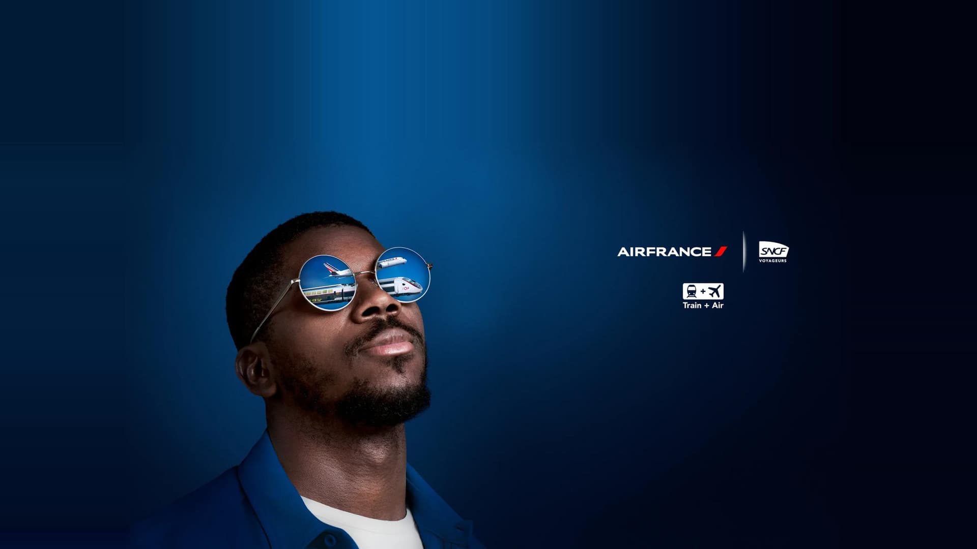 Visuel de la campagne Train + Air d'Air France et SNCF Voyageurs : un homme aux lunettes rondes où se reflètent un avion et un TGV