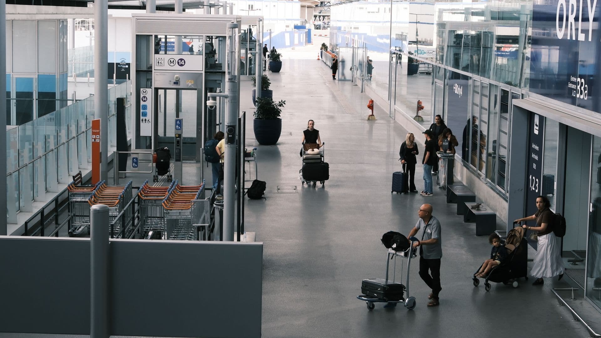 Voyageurs avec leurs valises et chariots dans un hall de l’aéroport Paris-Orly