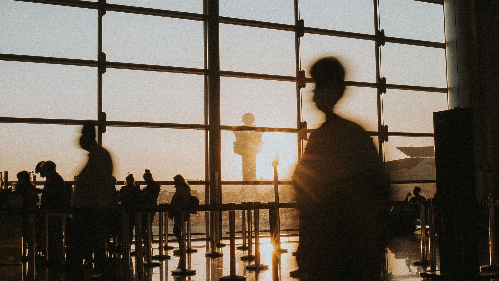 Silhouettes de voyageurs dans un terminal d’aéroport baigné de lumière