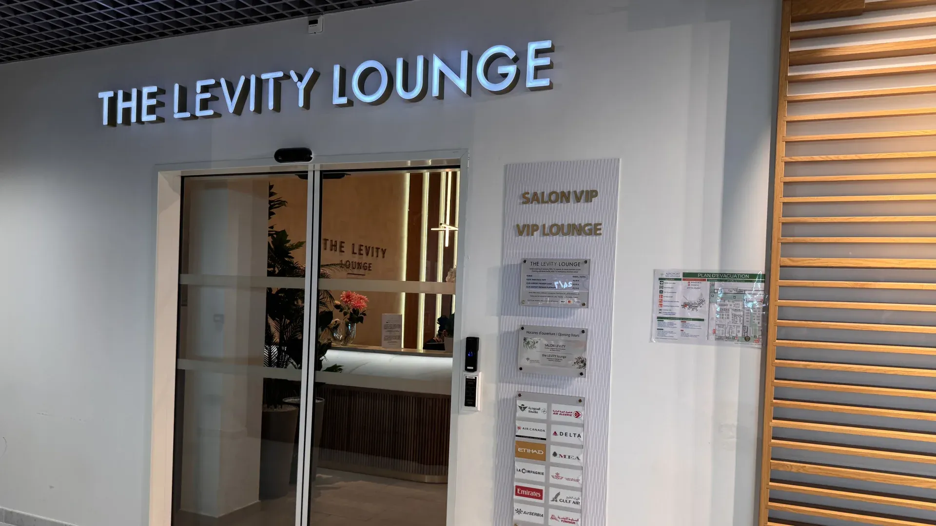 Entrée du Levity Lounge à l'aéroport de Nice, avec l'enseigne lumineuse, les portes vitrées et les logos des compagnies partenaires