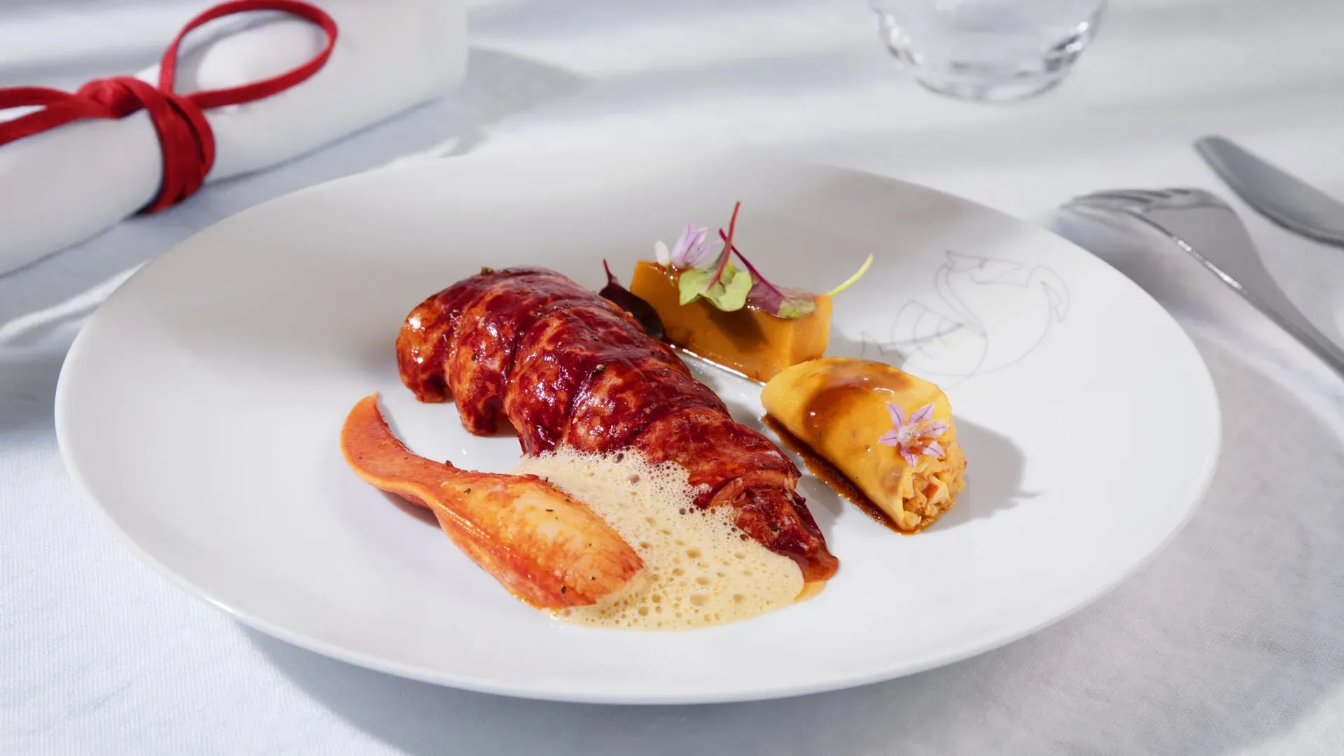 Homard cuit au court-bouillon servi avec une sauce mousseuse sur assiette blanche en cabine La Première d'Air France