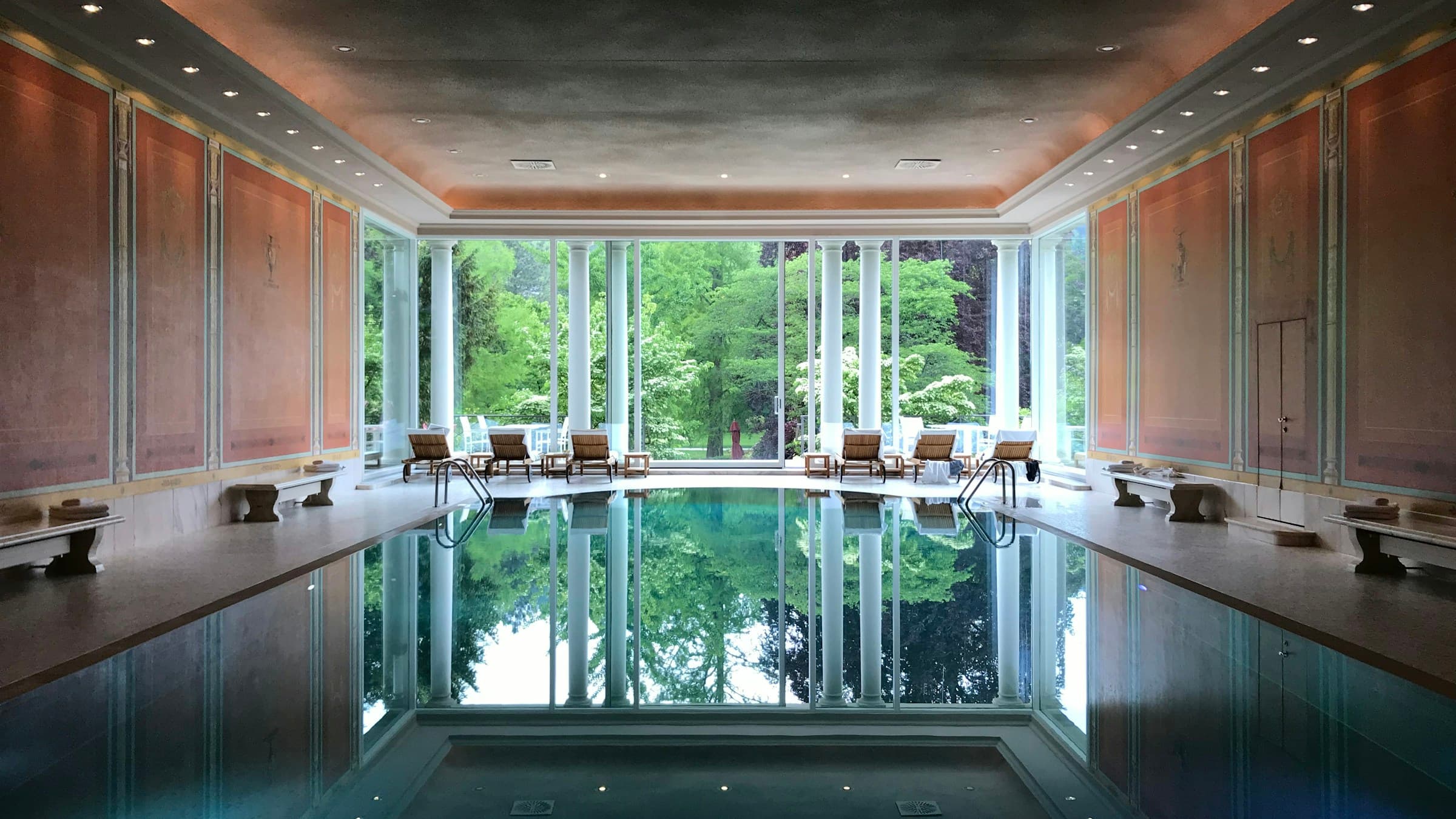 Photo d’illustration : bassin de spa intérieur et transats devant de grandes baies vitrées ouvertes sur les arbres