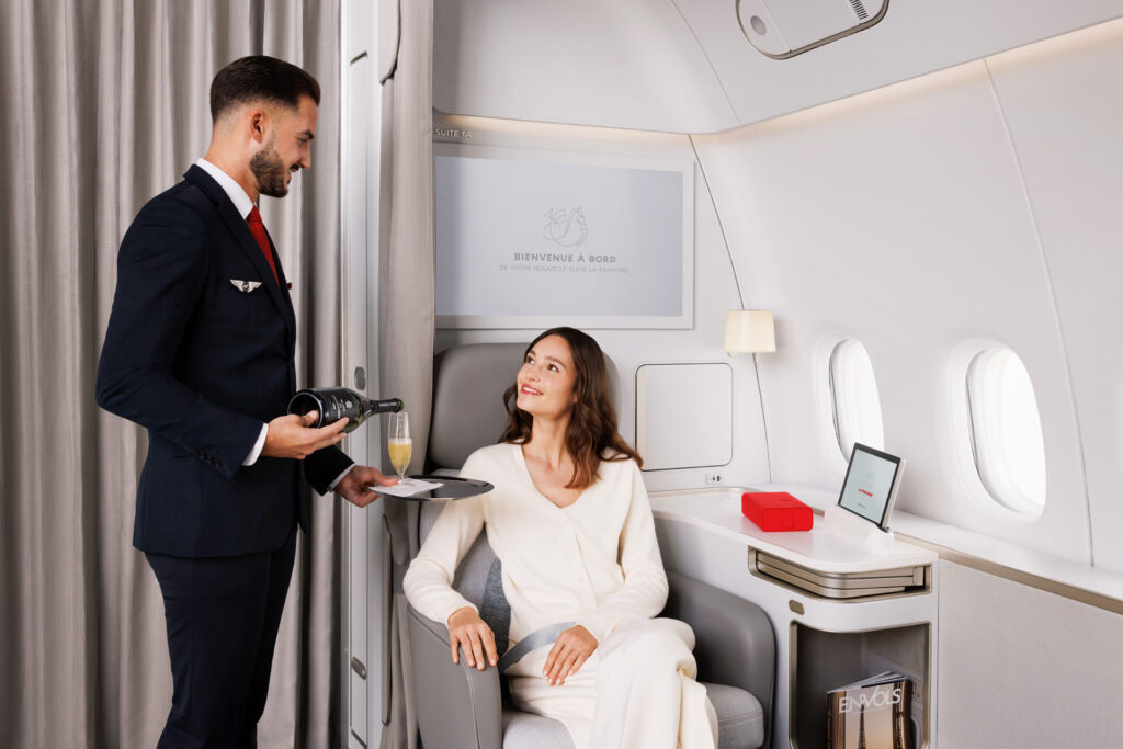 Un steward d'Air France sert du champagne à une passagère assise en cabine La Première.
