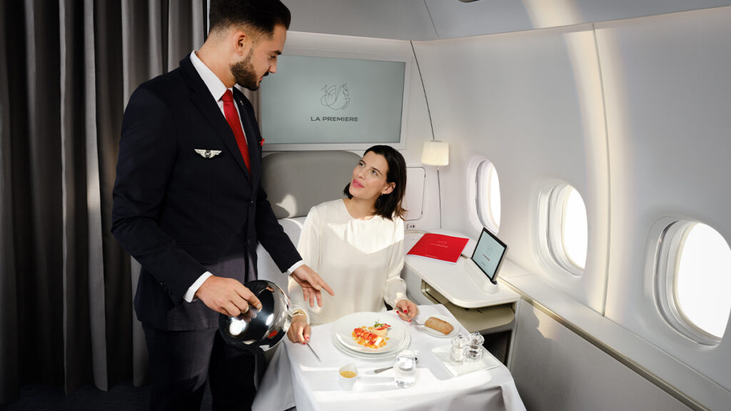 Un passager est servi par un membre d'équipage Air France en cabine La Première.