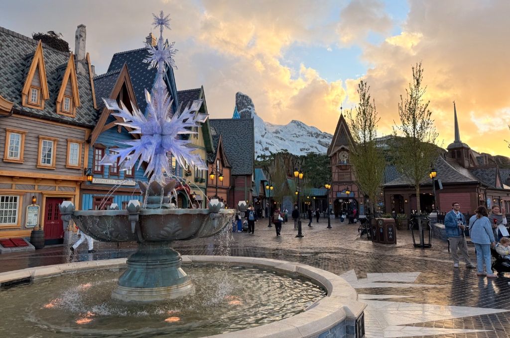 Fontaine avec flocons de neige illuminés dans un village norvégien à Disney Adventure World au coucher du soleil.