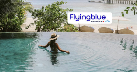 Une femme se relaxe dans une piscine à débordement avec vue sur la plage, accompagnée du logo "Flying Blue Air France KLM