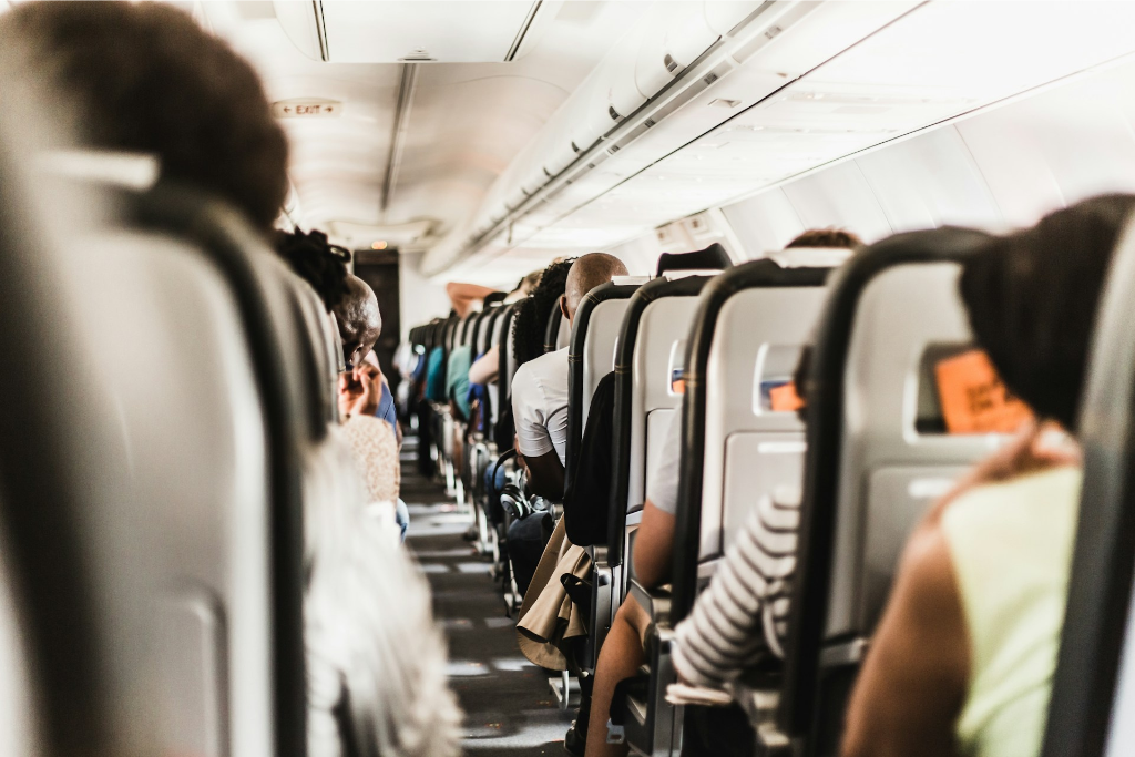 Cabine d’avion avec des passagers assis pendant un vol commercial, illustration des droits des passagers aériens en cas de retard ou d’annulation.