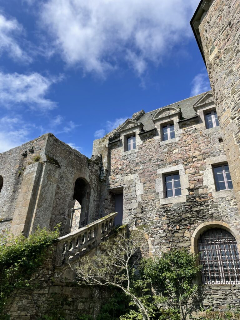 Façade en pierre de l'Abbaye de Beauport avec escalier ancien et ciel bleu nuageux.