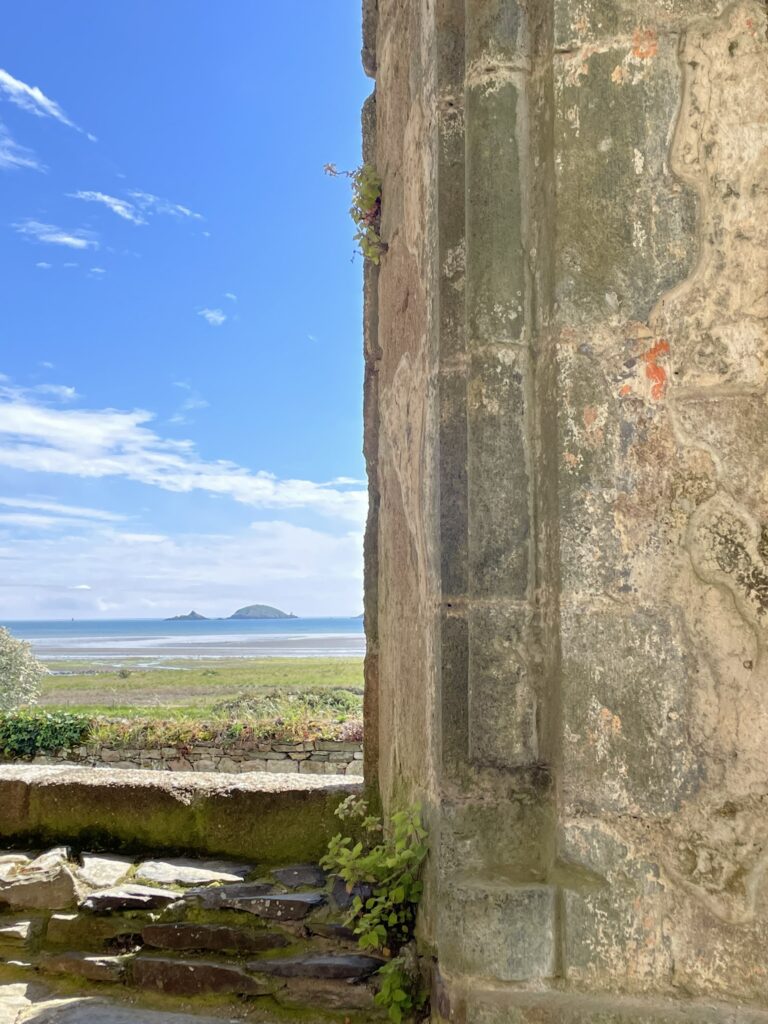 Mur de pierre de l'abbaye de Beauport avec vue sur la mer et deux îlots lointains.