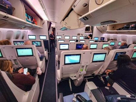 Cabine Premium Economy d'Air France avec sièges inclinables, écrans individuels et passagers installés en vol.