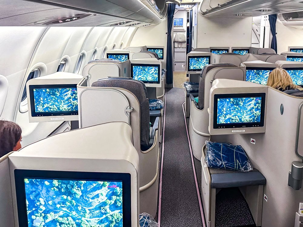 Cabine affaires d'un Airbus A330 d'Air Mauritius avec sièges inclinables et écrans individuels allumés.
