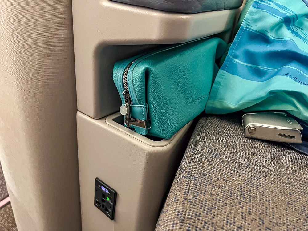 Pochette turquoise Air Mauritius rangée dans un siège de classe affaires d'un Airbus A330.
