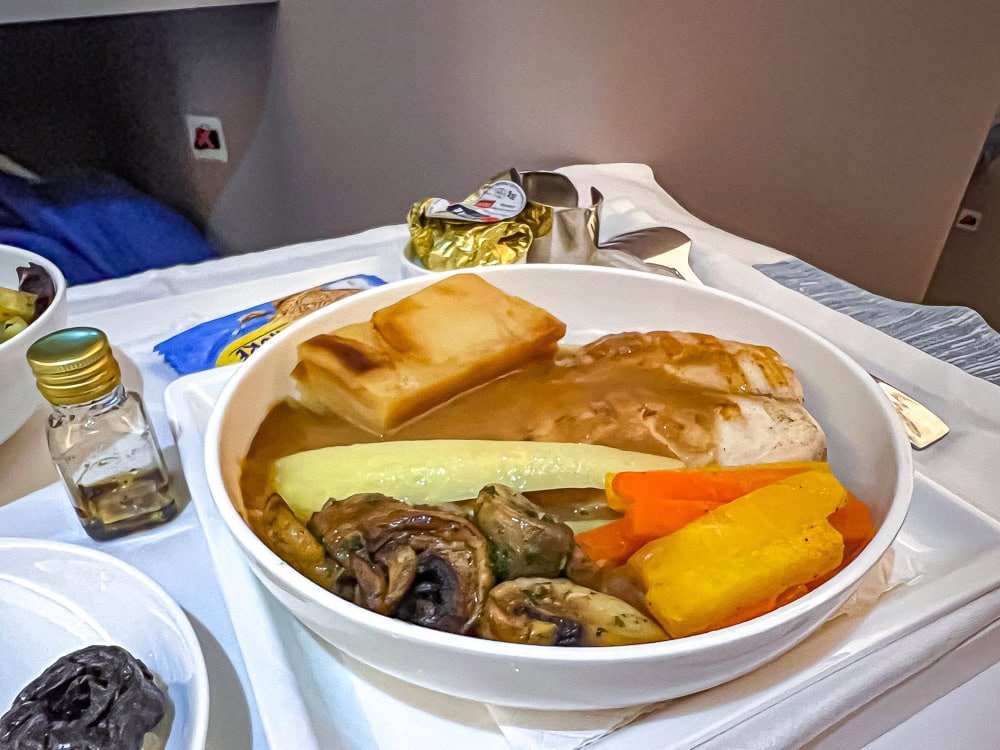 Repas servi à bord d'un vol Air Mauritius avec poulet, légumes et gratin sur plateau blanc.