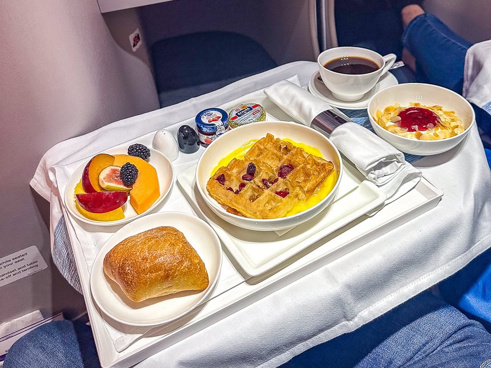 Petit-déjeuner servi à bord d'Air Mauritius avec gaufre, fruits frais, viennoiserie et café.