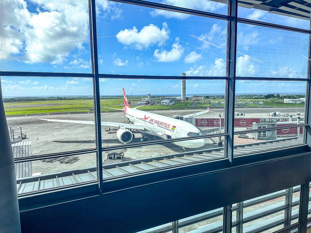 Avion Air Mauritius stationné à la porte d'embarquement, vu à travers les vitres de l'aéroport.