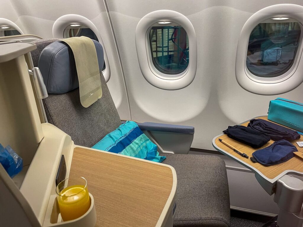 Siège en classe affaires Air Mauritius avec trousse de confort et boisson à bord d'un Airbus.