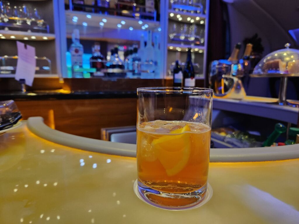 Cocktail au bar de l'Airbus A380 Emirates en classe Affaires, avec bouteilles et verres rétroéclairés