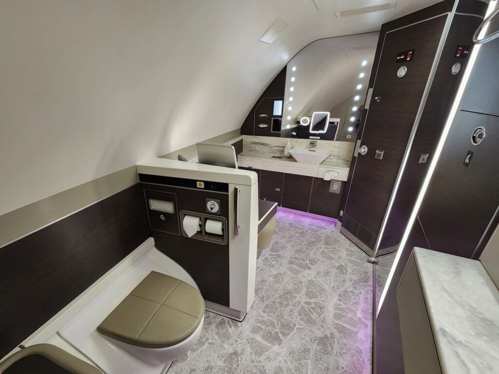 Salle de bain spacieuse à bord d'un avion Singapore Airlines avec lavabo moderne et finitions beige et bois