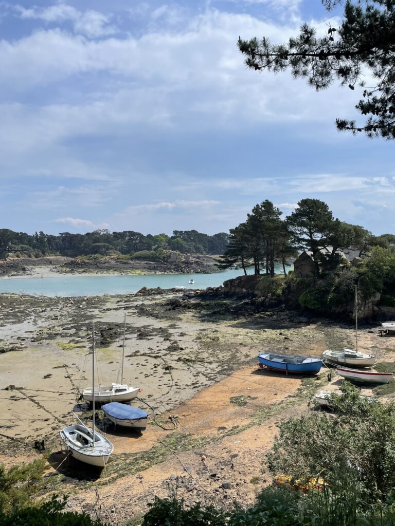 Petits voiliers échoués sur la grève rocheuse de l'île de Bréhat à marée basse sous ciel clair.