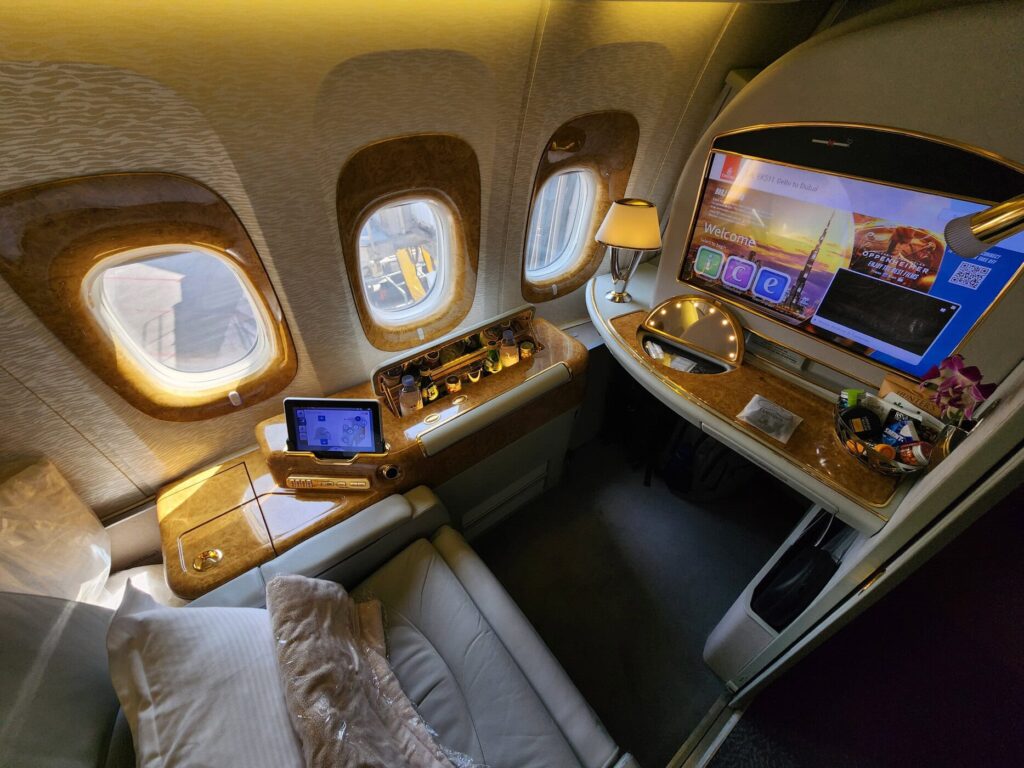 Suite de Première Classe Emirates sur Boeing 777 avec écran ICE, mini-bar et sièges en cuir beige