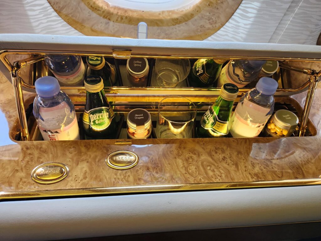 Mini-bar doré dans la suite de Première Classe Emirates avec bouteilles d'eau, Perrier et collations