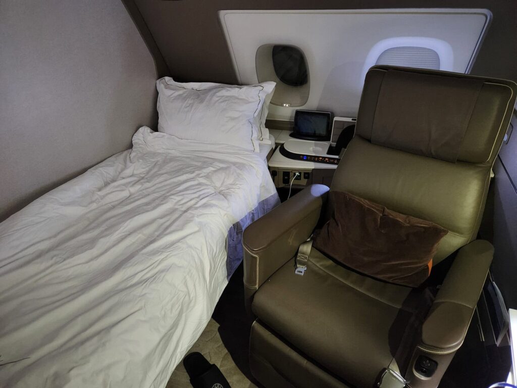 Suite de première classe Singapore Airlines avec lit préparé et large fauteuil en cuir sur A380.