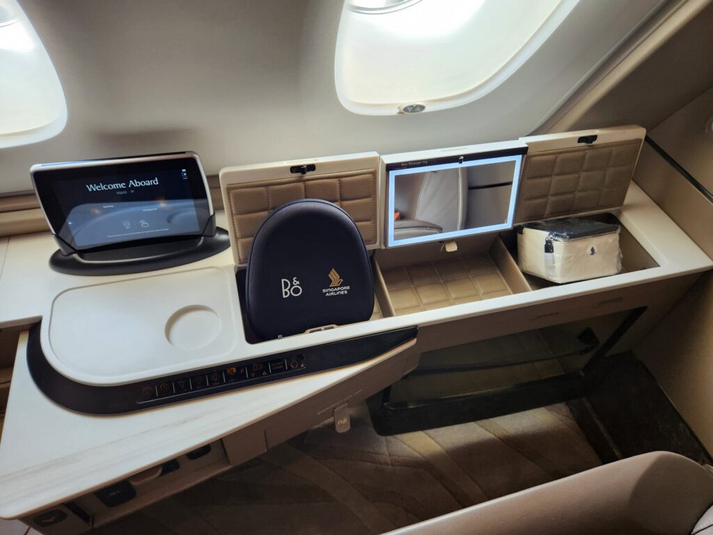 Siège en Première Classe Singapore Airlines avec écran, casque Bang & Olufsen et trousse de voyage.