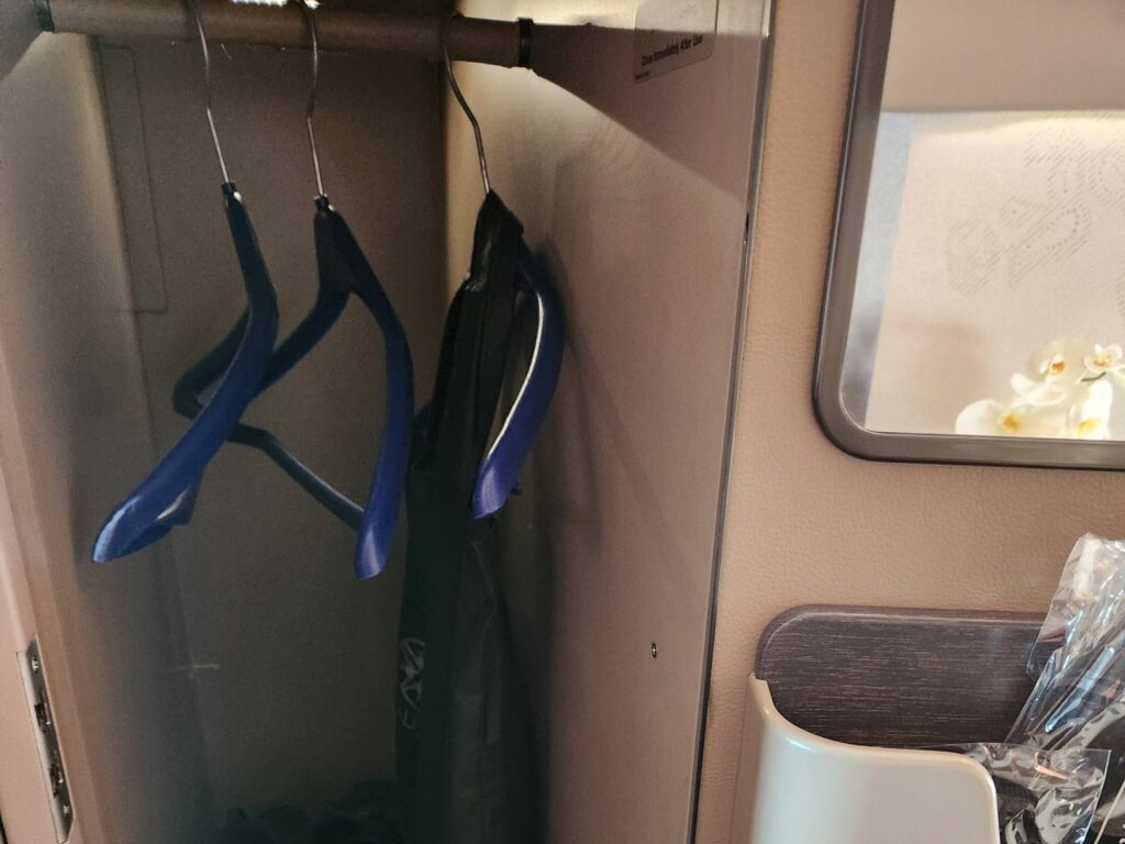 Penderie individuelle avec cintres bleus dans une suite de première classe Singapore Airlines.