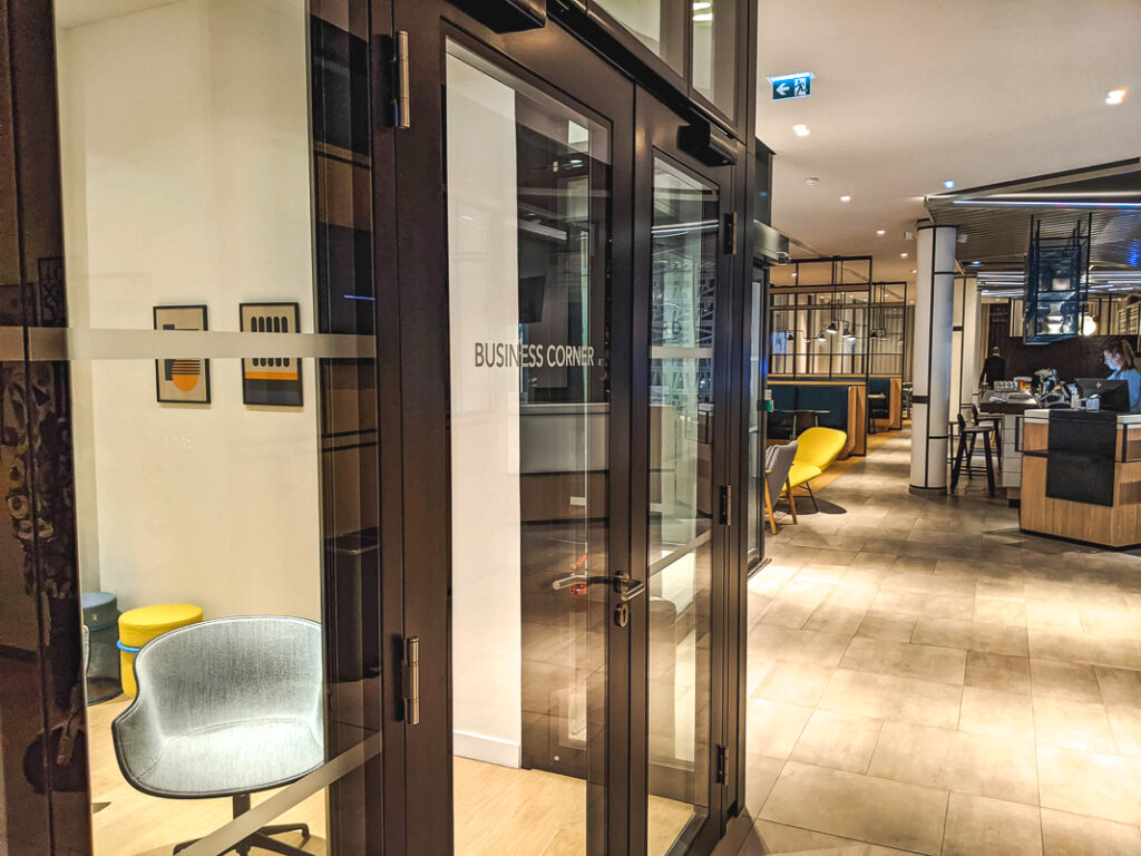 Espace business vitré avec fauteuil gris, jouxtant le lobby moderne et lumineux du Courtyard Paris Créteil.