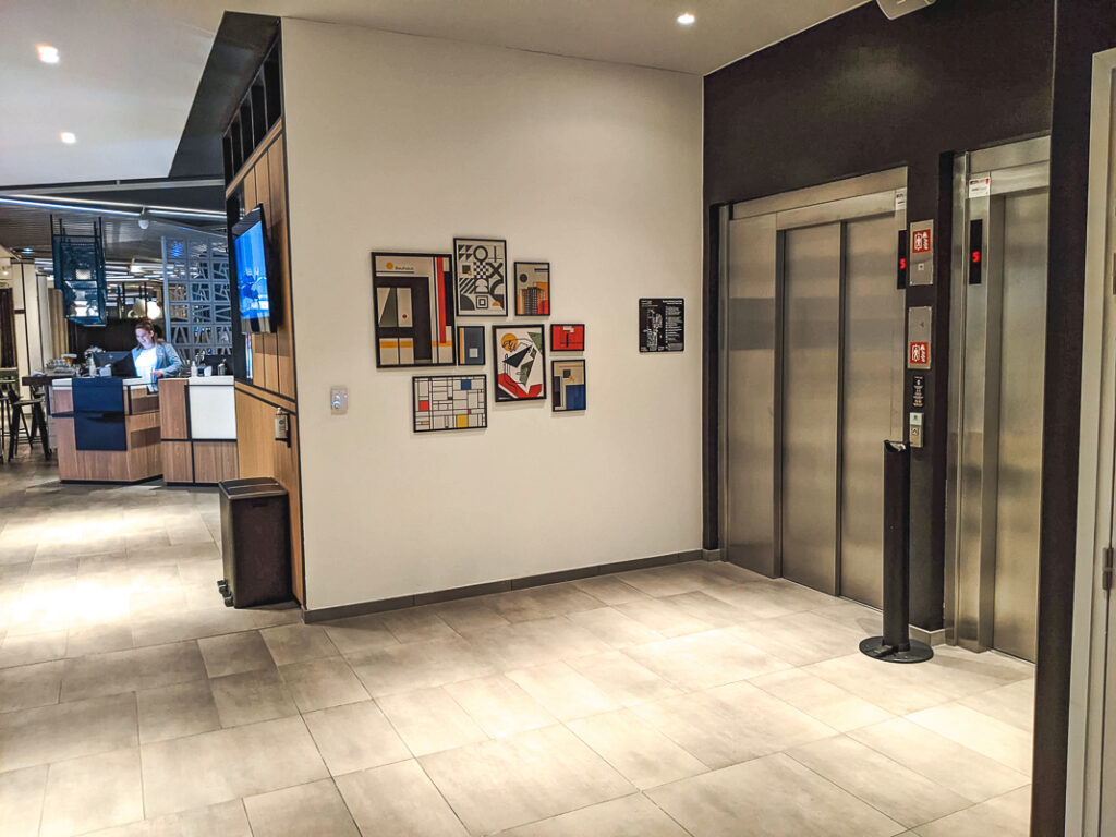 Hall moderne du Courtyard Paris Créteil avec deux ascenseurs et mur décoré de cadres colorés.