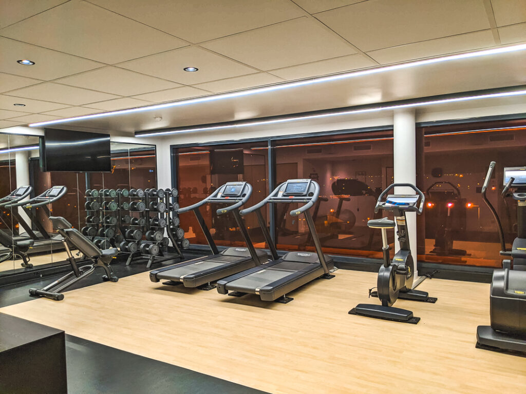 Salle de sport lumineuse avec tapis de course, haltères et vélo stationnaire au Courtyard by Marriott Paris Créteil.