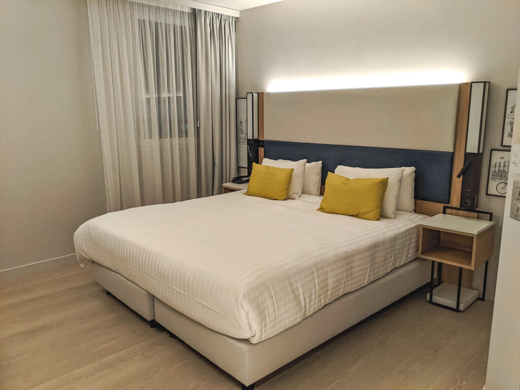 Chambre moderne du Courtyard by Marriott Paris Créteil avec grand lit double et coussins jaunes.