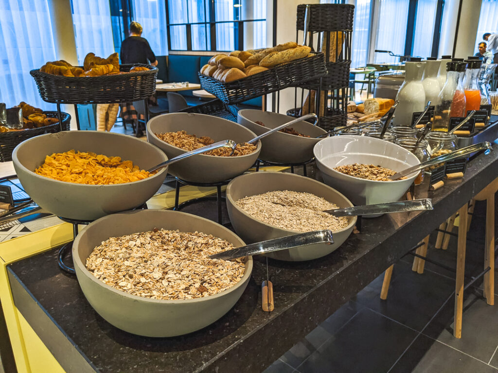 Buffet de petit-déjeuner avec bols de céréales, granola et pains dans la salle du Courtyard Paris Créteil.