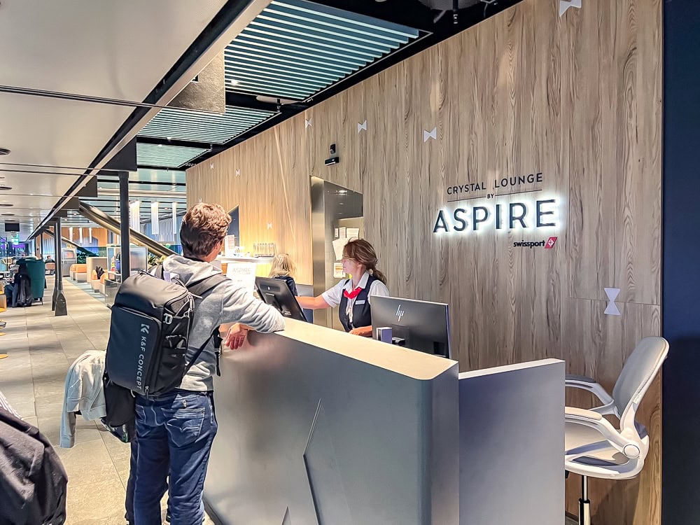 Comptoir d'accueil du Crystal Lounge Aspire de Swissport à l'aéroport de Genève avec un passager.