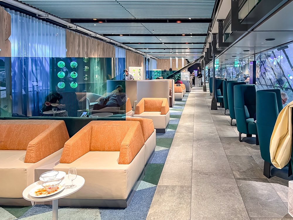 Salon Aspire à l'aéroport de Genève avec fauteuils orange et espaces détente modernes lumineux.