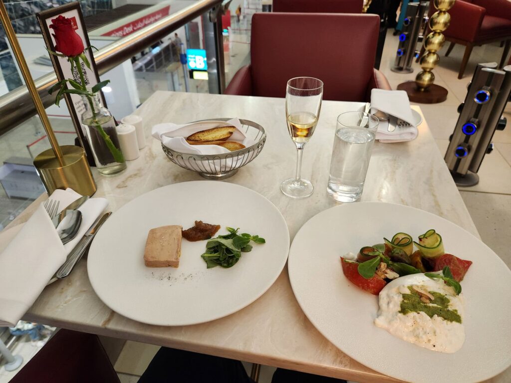Repas gastronomique servi au Emirates First Class Lounge de l'aéroport de Dubaï, avec foie gras et burrata.
