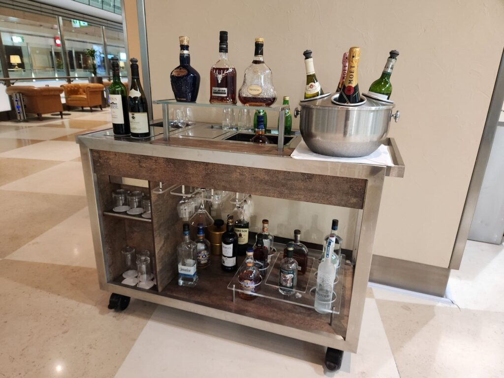 Chariot à boissons avec alcools variés au salon Emirates, comprenant champagnes, vins et spiritueux.
