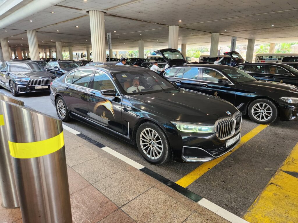 Plusieurs voitures BMW noires Emirates Chauffeur Drive attendent les passagers à l'aéroport de Dubaï.