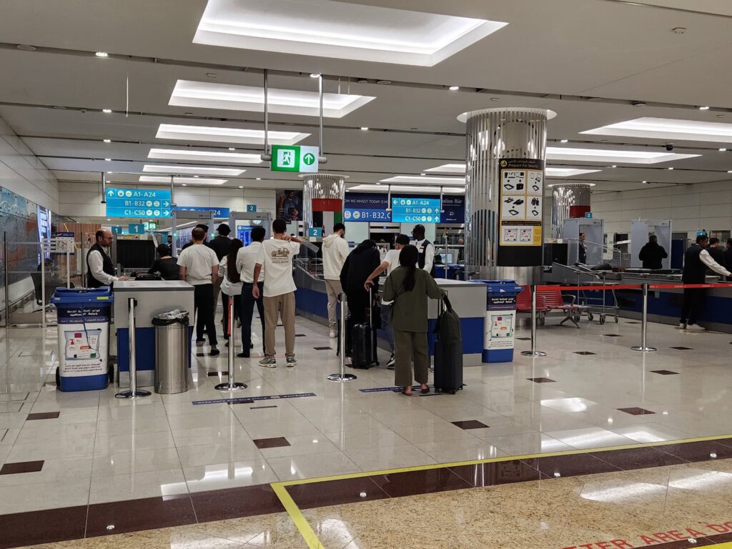 Passagers faisant la queue au contrôle de sécurité de l'aéroport de Dubaï, devant les comptoirs Emirates.