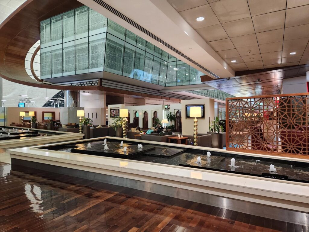 Salon Emirates avec fontaines et espaces détente au terminal de l'aéroport de Dubaï DXB.