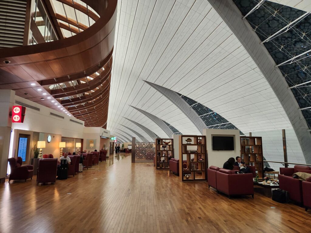 Salon Emirates avec fauteuils rouges et plafond voûté moderne à l'aéroport international de Dubaï.