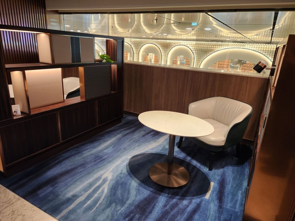 Espace privatif avec fauteuil et table au salon Singapore Airlines à l'aéroport de Singapour.