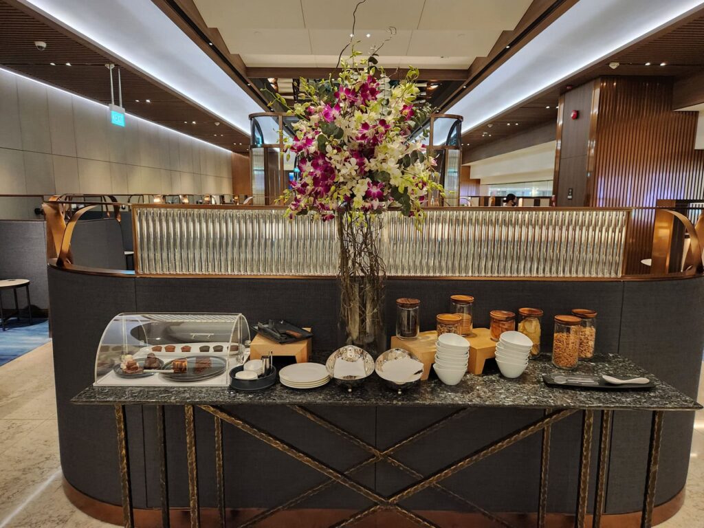 Buffet élégant avec collations et fleurs fraîches au salon Singapore Airlines à l'aéroport de Singapour.