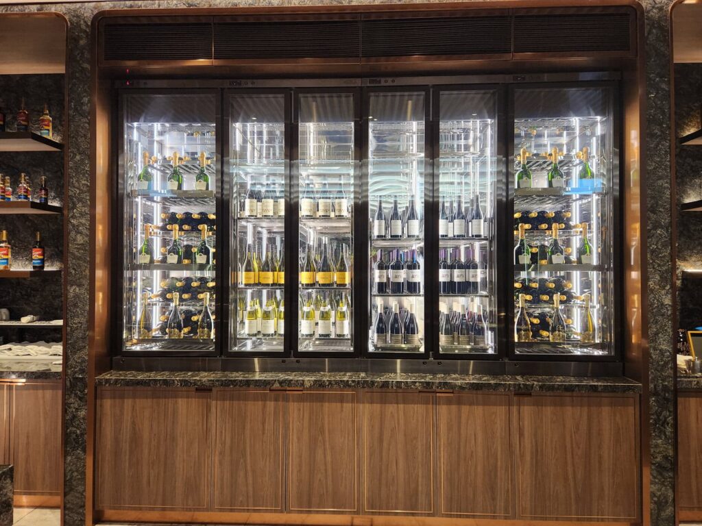 Vue d'une cave à vins réfrigérée avec bouteilles de champagne et vins au salon Singapore Airlines.