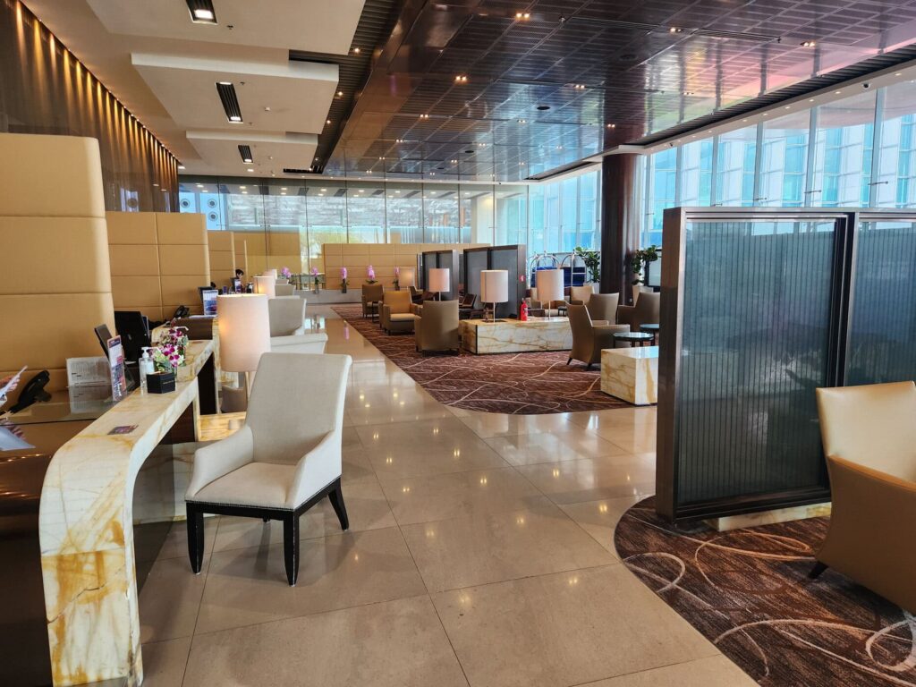 Salon raffiné de Singapore Airlines avec sièges beiges, marbre clair et larges baies vitrées lumineuses.