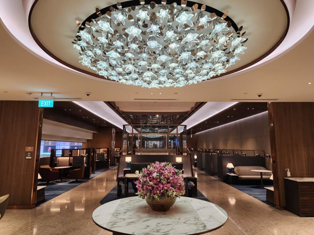 Salon Singapore Airlines avec lustre floral, fauteuils privés et décoration élégante en bois et marbre.