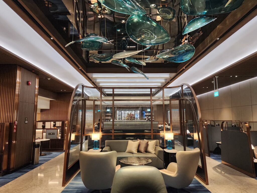 Salon élégant de Singapore Airlines avec sièges confortables, lampes design et décoration moderne en verre suspendu.