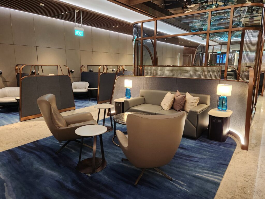 Salon Singapore Airlines raffiné avec fauteuils et canapés sur moquette bleue à l'aéroport de Singapour.
