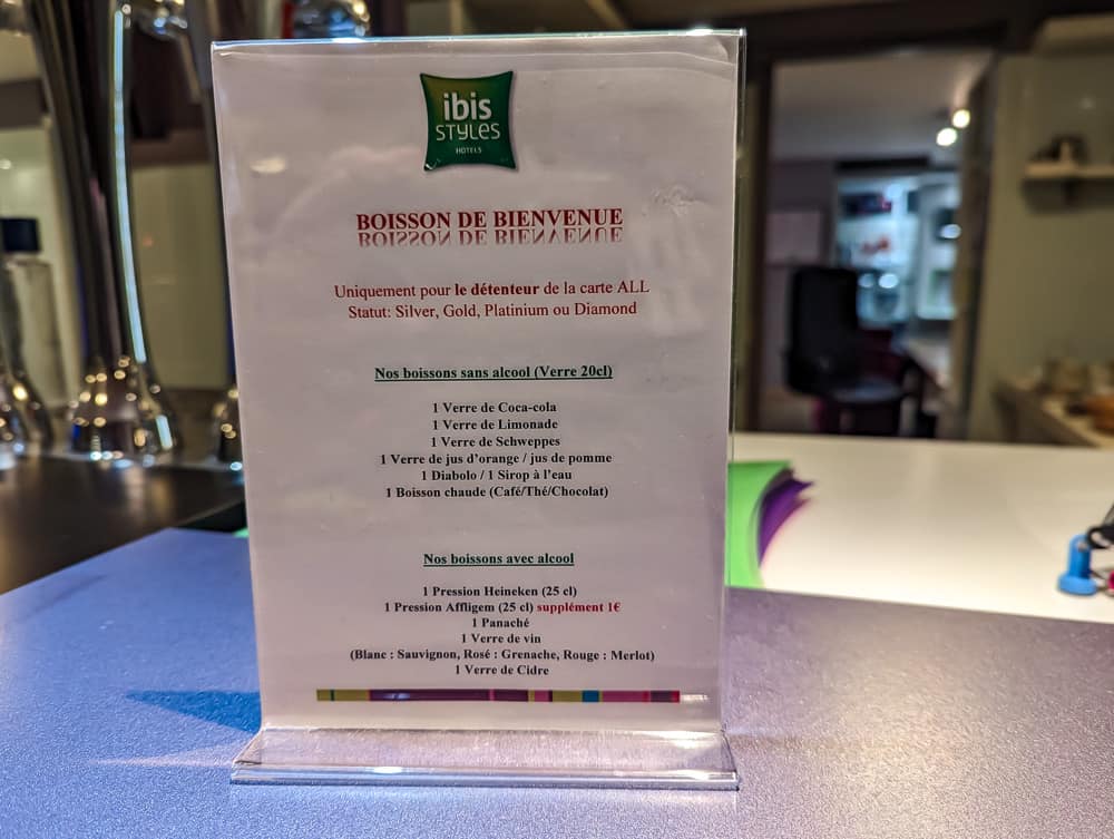 Carte posée sur le comptoir du bar listant les boissons de bienvenue offertes à l'hôtel Ibis Styles Ouistreham